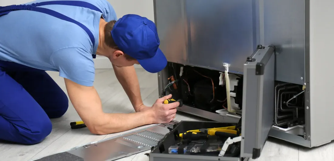 Appliance repair in Houston TX - technician repairing a refrigerator at a Houston home